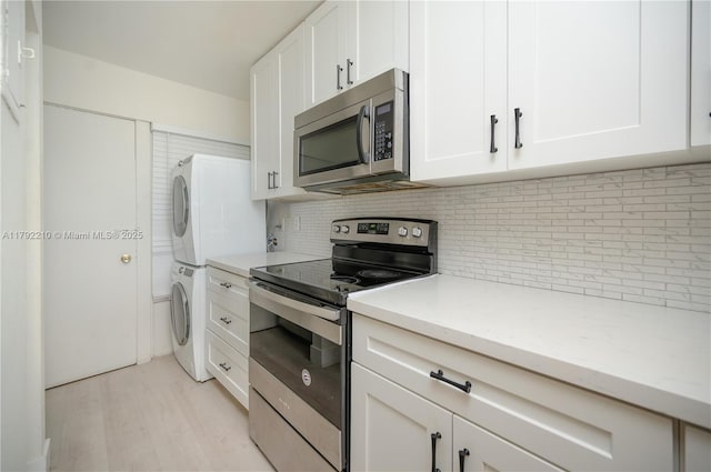 9210 Fontainebleau Blvd Unit 505, Miami, FL 33172 - kitchen with appliances with stainless steel finishes, stacked washer and clothes dryer, backsplash, light wood-type flooring, and white cabinetry