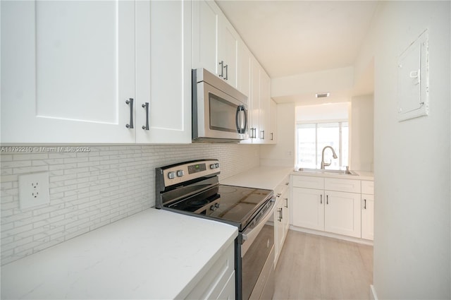 9210 Fontainebleau Blvd Unit 505, Miami, FL 33172 - kitchen with stainless steel appliances, a sink, backsplash, white cabinets, and light wood-type flooring