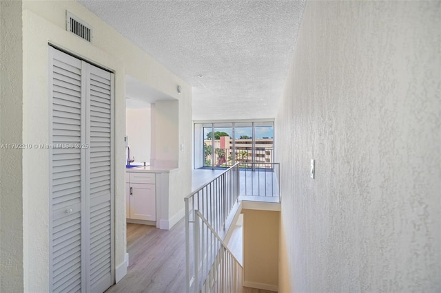 9210 Fontainebleau Blvd Unit 505, Miami, FL 33172 - hall featuring a textured ceiling, an upstairs landing, and light wood-type flooring