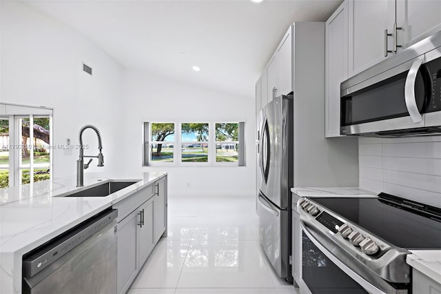 11069 Rios Rd, Boca Raton, FL 33498 - kitchen with visible vents, lofted ceiling, light stone countertops, a sink, and stainless steel appliances