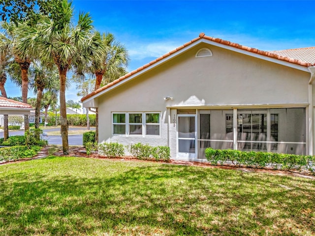 11069 Rios Rd, Boca Raton, FL 33498 - back of property featuring a sunroom, stucco siding, a yard, and a tile roof