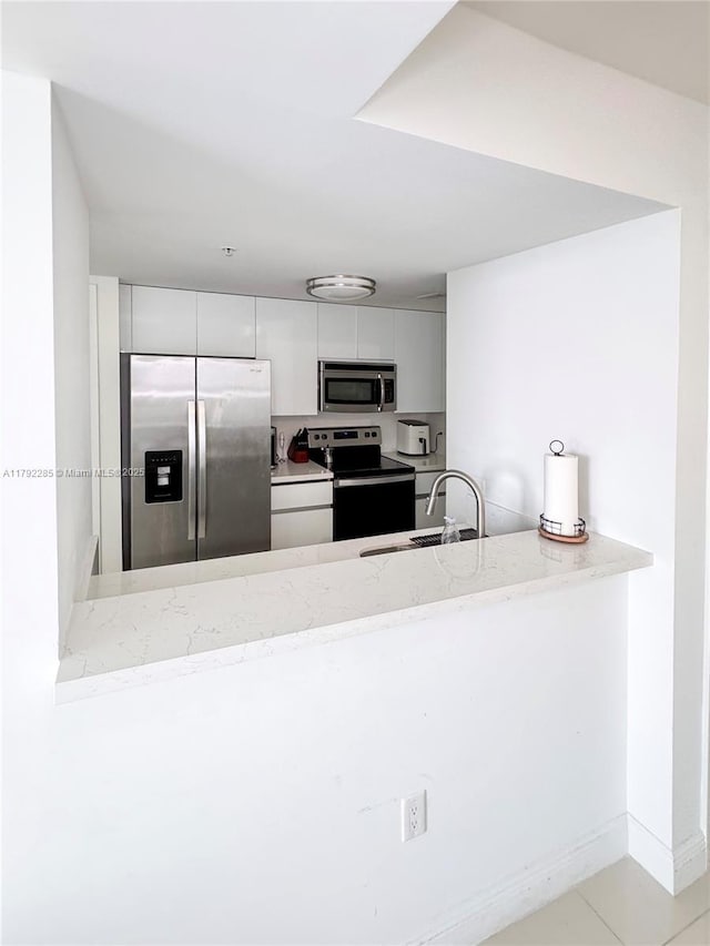 kitchen with white cabinets, a sink, stainless steel appliances, modern cabinets, and a peninsula