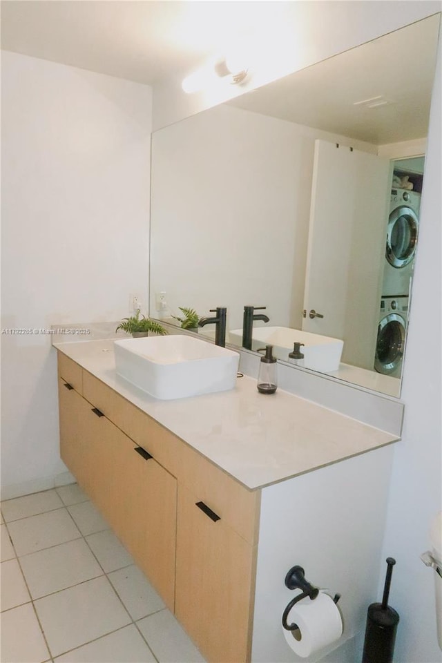bathroom featuring stacked washing maching and dryer, tile patterned flooring, and vanity