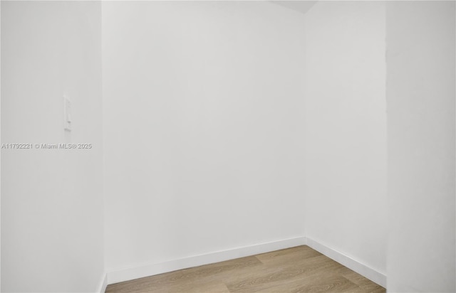 spare room featuring baseboards and light wood-style floors