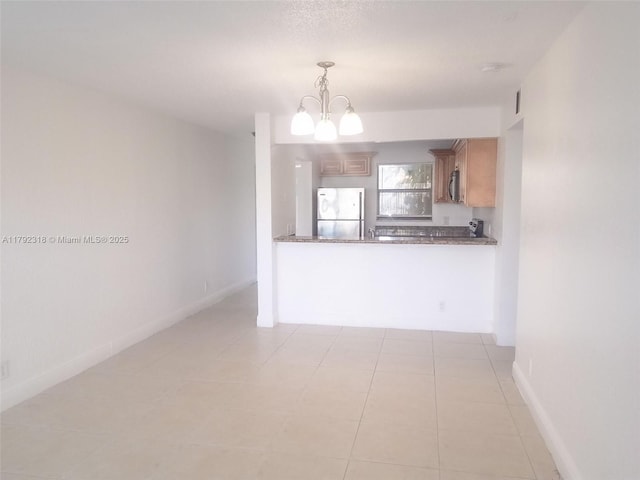 interior space featuring hanging light fixtures, a chandelier, stainless steel appliances, baseboards, and light tile patterned flooring