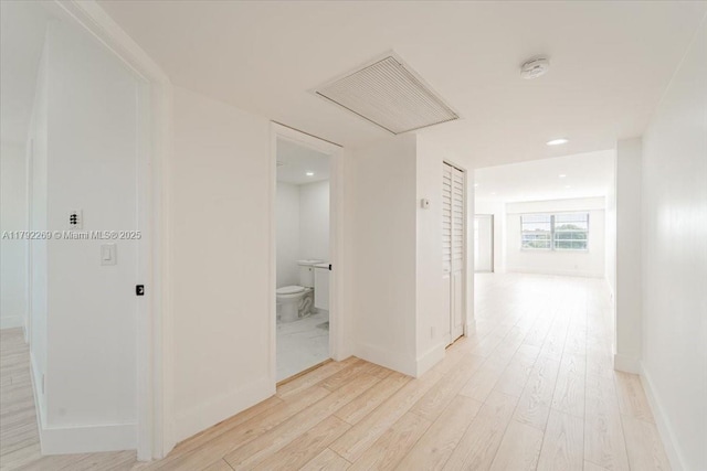 hall featuring light wood finished floors, recessed lighting, visible vents, and baseboards