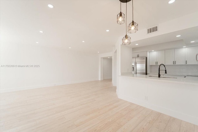 kitchen with stainless steel refrigerator with ice dispenser, visible vents, light countertops, and a sink
