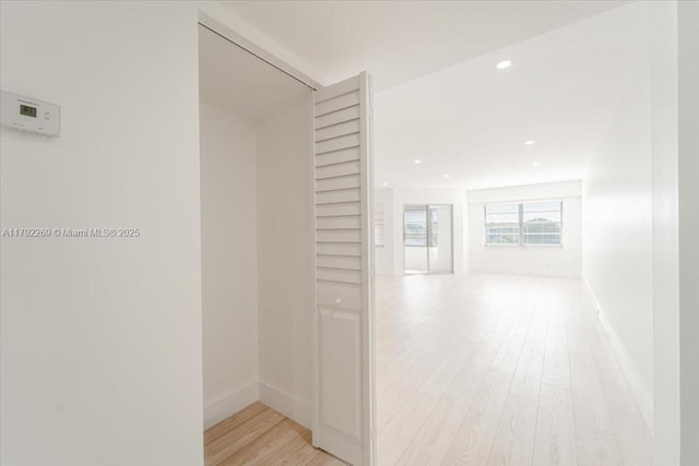 corridor with baseboards, recessed lighting, and light wood finished floors