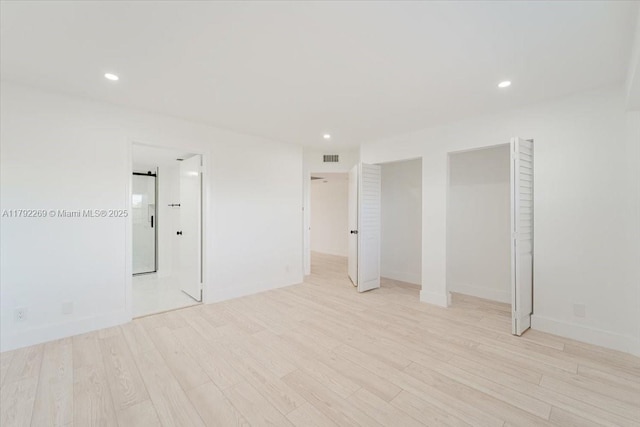 unfurnished bedroom featuring multiple closets, recessed lighting, and light wood-style flooring