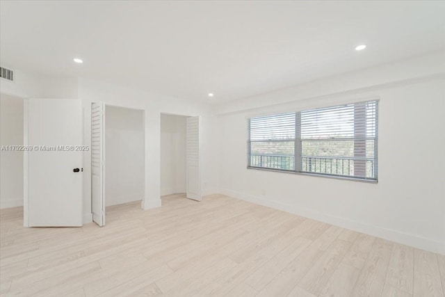 unfurnished bedroom with recessed lighting, visible vents, light wood-style flooring, and multiple closets