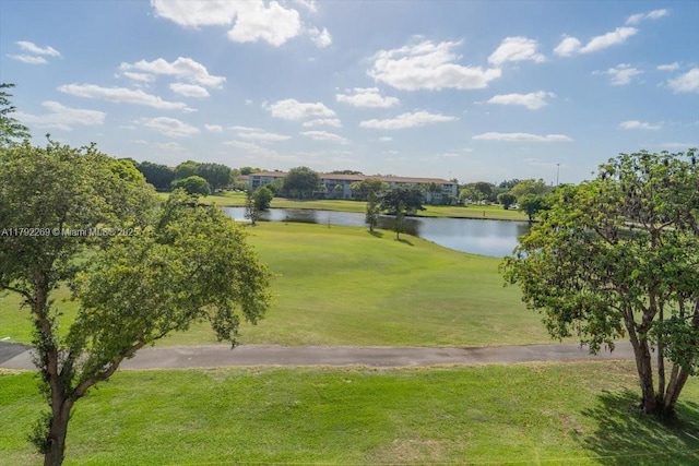 view of property's community with a yard, a water view, and view of golf course