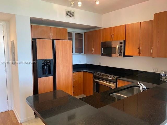 2775 NE 187th St Unit 311, Aventura, FL 33180 - kitchen with appliances with stainless steel finishes, brown cabinetry, a sink, and glass insert cabinets