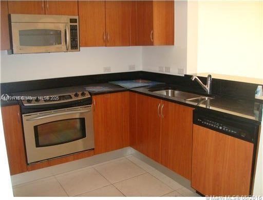 kitchen with dark countertops, brown cabinets, appliances with stainless steel finishes, and a sink