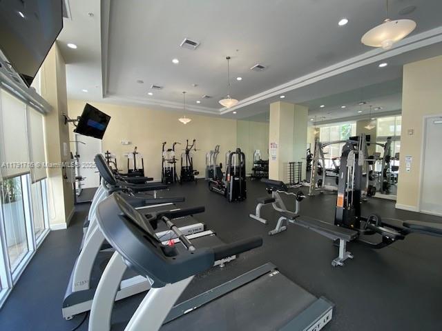 workout area with recessed lighting, visible vents, and a tray ceiling
