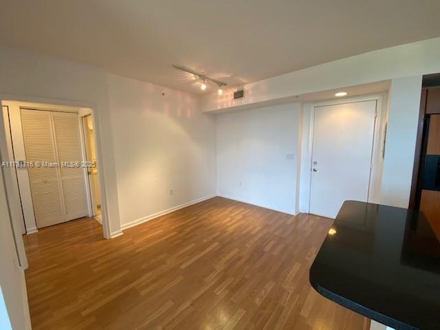 unfurnished bedroom with track lighting, wood finished floors, baseboards, visible vents, and a ceiling fan