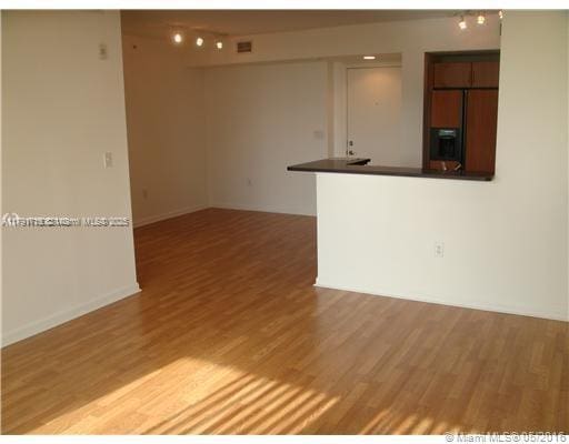 interior space featuring rail lighting, light wood-style flooring, and baseboards