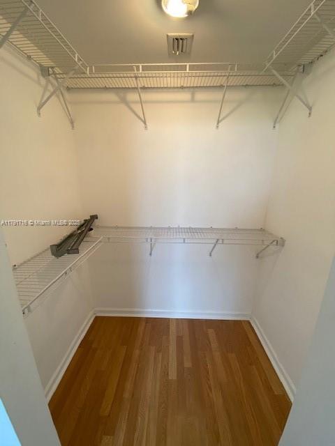 walk in closet with wood finished floors