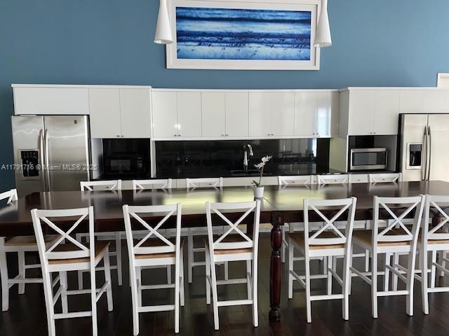 kitchen featuring a sink, stainless steel appliances, a kitchen breakfast bar, a spacious island, and white cabinets