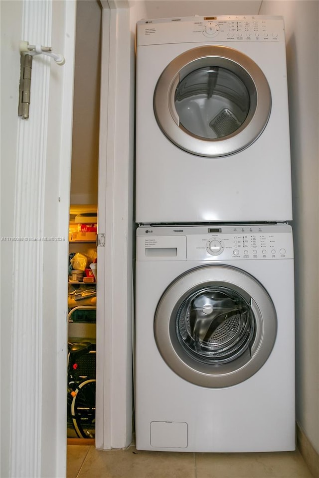 washroom with stacked washer / drying machine, tile patterned flooring, and laundry area