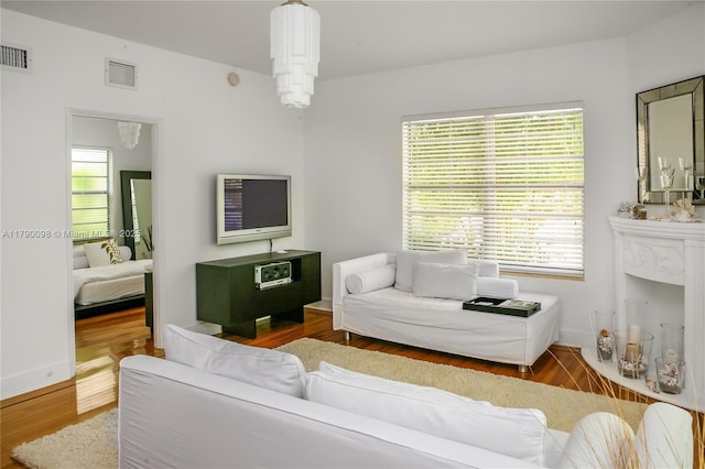 living area featuring visible vents and wood finished floors