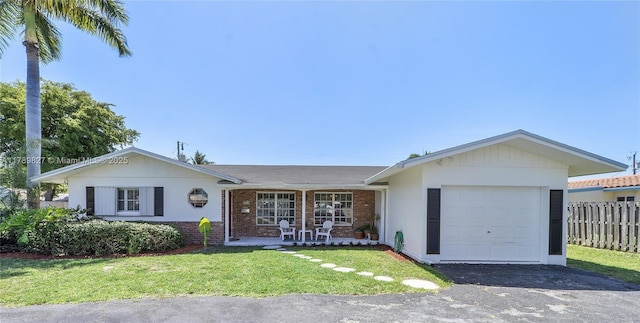 single story home featuring a garage, aphalt driveway, fence, a front yard, and brick siding
