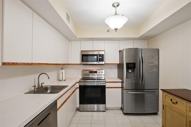 kitchen featuring light tile patterned floors, appliances with stainless steel finishes, light countertops, white cabinets, and a sink