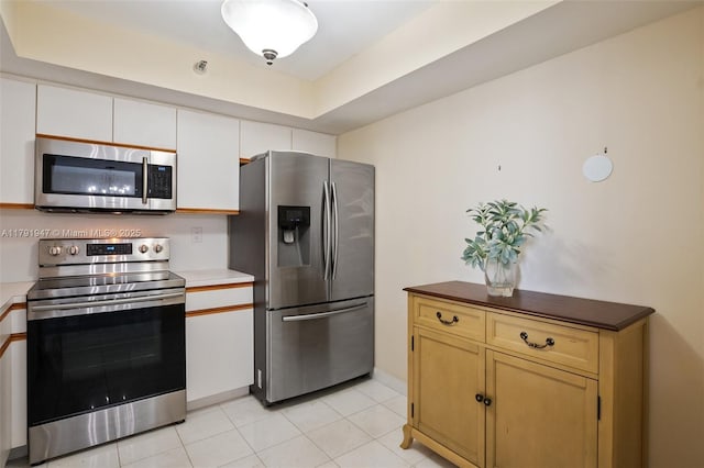 kitchen with appliances with stainless steel finishes, light tile patterned flooring, and baseboards