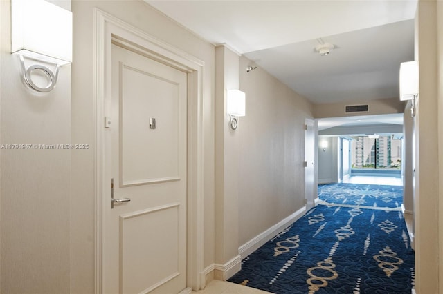 hall with carpet floors, visible vents, and baseboards