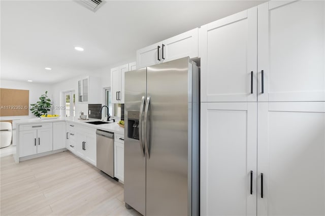 kitchen with recessed lighting, a sink, stainless steel appliances, visible vents, and white cabinetry