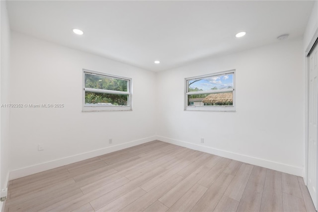 empty room featuring light wood finished floors, recessed lighting, baseboards, and plenty of natural light