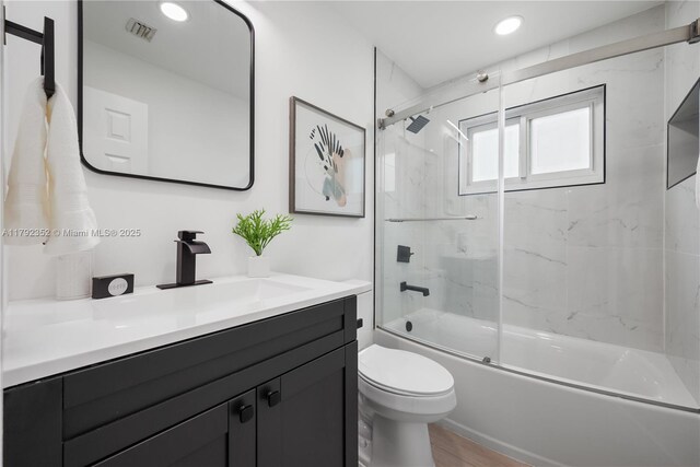full bathroom featuring recessed lighting, vanity, bath / shower combo with glass door, toilet, and visible vents