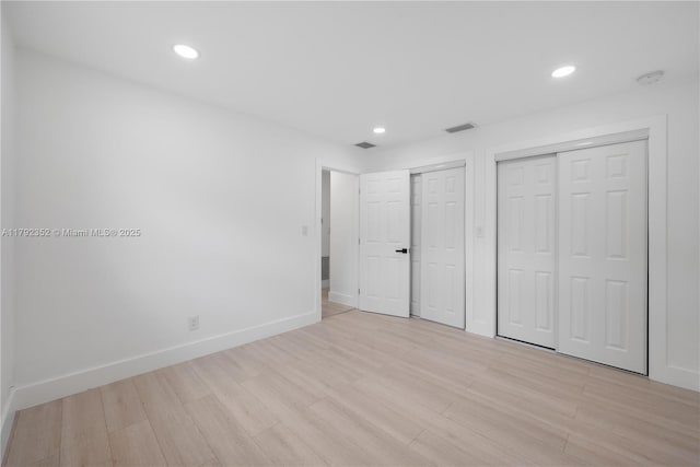 unfurnished bedroom featuring recessed lighting, visible vents, light wood-style flooring, baseboards, and multiple closets
