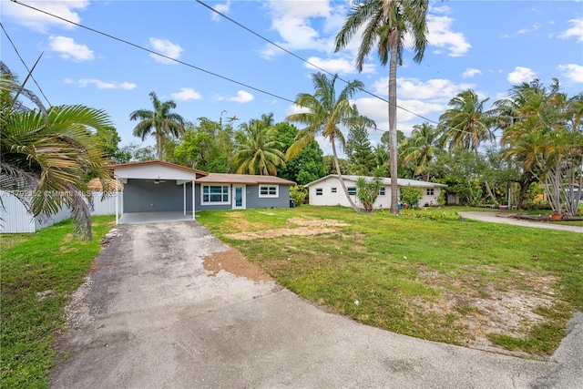 ranch-style house featuring fence, aphalt driveway, a front lawn, and an attached carport