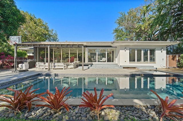 rear view of property featuring an outdoor pool, a patio, and a sunroom