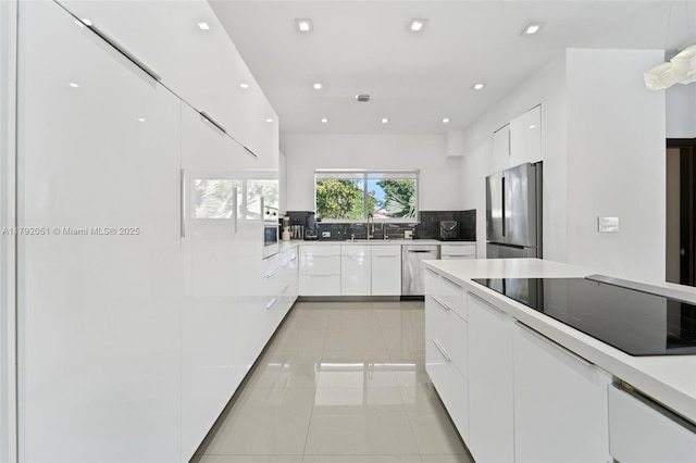 kitchen featuring a sink, modern cabinets, stainless steel appliances, tasteful backsplash, and white cabinets
