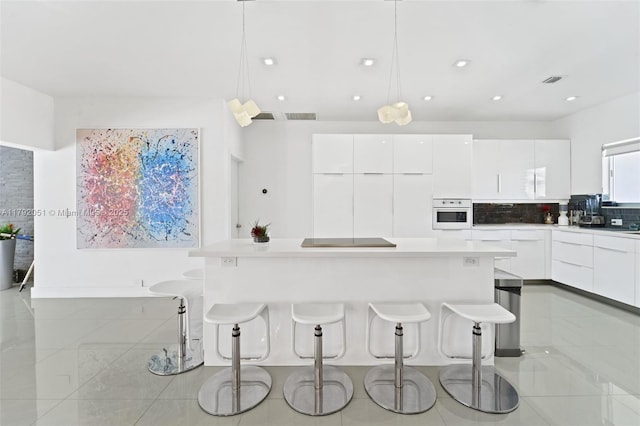 kitchen featuring white cabinetry, white oven, a kitchen breakfast bar, and modern cabinets