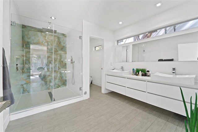full bathroom featuring a shower stall, a sink, double vanity, baseboards, and toilet