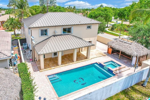 rear view of property featuring metal roof, a standing seam roof, and stucco siding