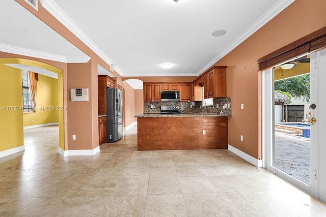 kitchen featuring appliances with stainless steel finishes, crown molding, brown cabinetry, and arched walkways