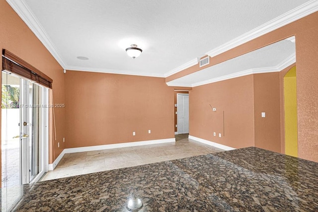 tiled spare room featuring crown molding, arched walkways, visible vents, and baseboards