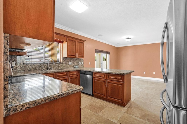 kitchen featuring brown cabinetry, stainless steel appliances, a sink, a peninsula, and crown molding