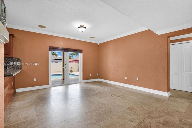 unfurnished living room featuring crown molding, a textured wall, and baseboards