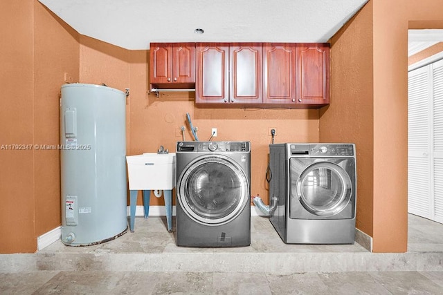 clothes washing area with a sink, baseboards, electric water heater, washer and clothes dryer, and cabinet space