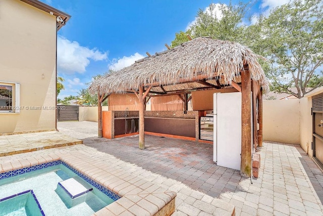 view of patio / terrace featuring a fenced in pool, a gazebo, area for grilling, a sink, and a fenced backyard