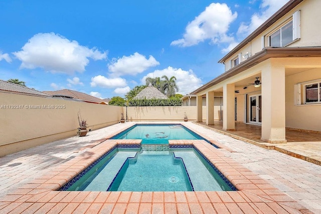 view of swimming pool featuring a pool with connected hot tub, a ceiling fan, a patio, and a fenced backyard