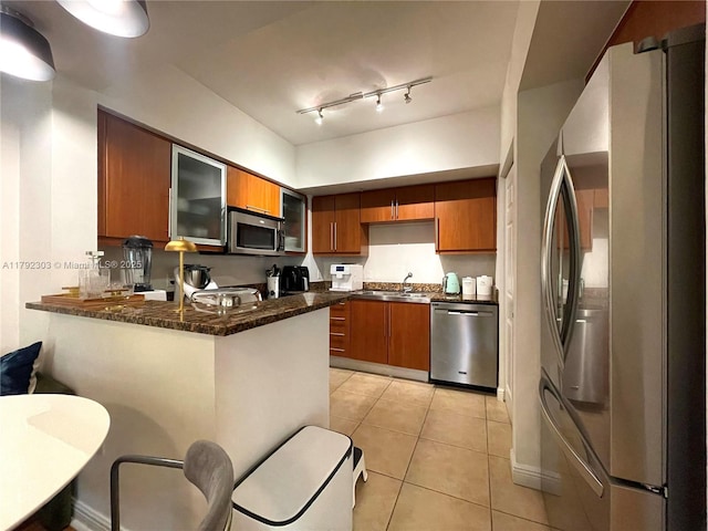 888 S Douglas Rd Unit 119, Coral Gables, FL 33134 - kitchen featuring brown cabinetry, light tile patterned floors, appliances with stainless steel finishes, a sink, and a peninsula
