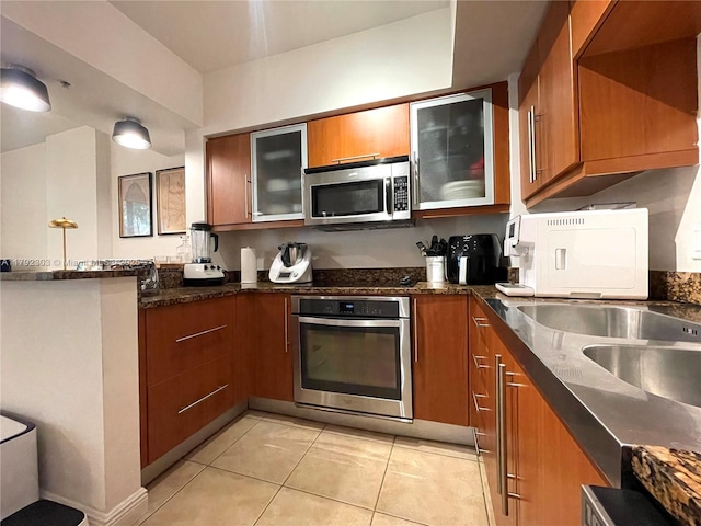 888 S Douglas Rd Unit 119, Coral Gables, FL 33134 - kitchen with light tile patterned floors, a peninsula, brown cabinets, and appliances with stainless steel finishes