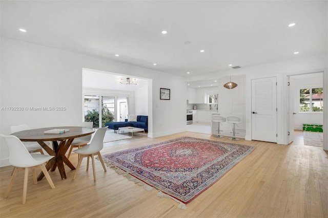 living room featuring light wood finished floors, recessed lighting, a notable chandelier, and baseboards