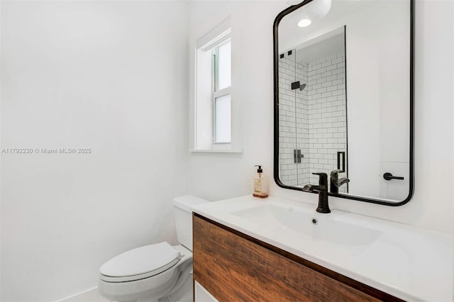 bathroom featuring toilet, a shower with shower door, and vanity