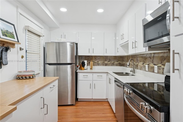 kitchen featuring backsplash, a sink, light countertops, white cabinets, and stainless steel appliances